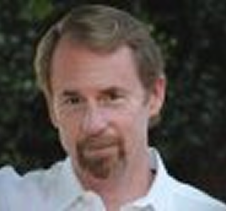 Portrait of a man with light brown hair and a beard, wearing a white shirt.