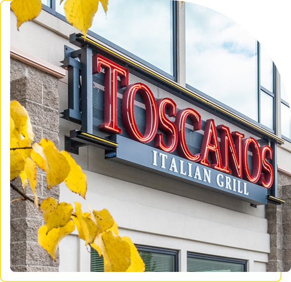 Exterior view of Toscano's Italian Grill with autumn leaves nearby.
