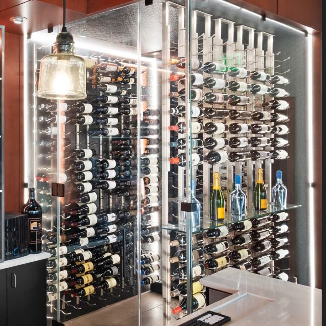 Modern glass-enclosed wine cellar filled with various wine bottles.