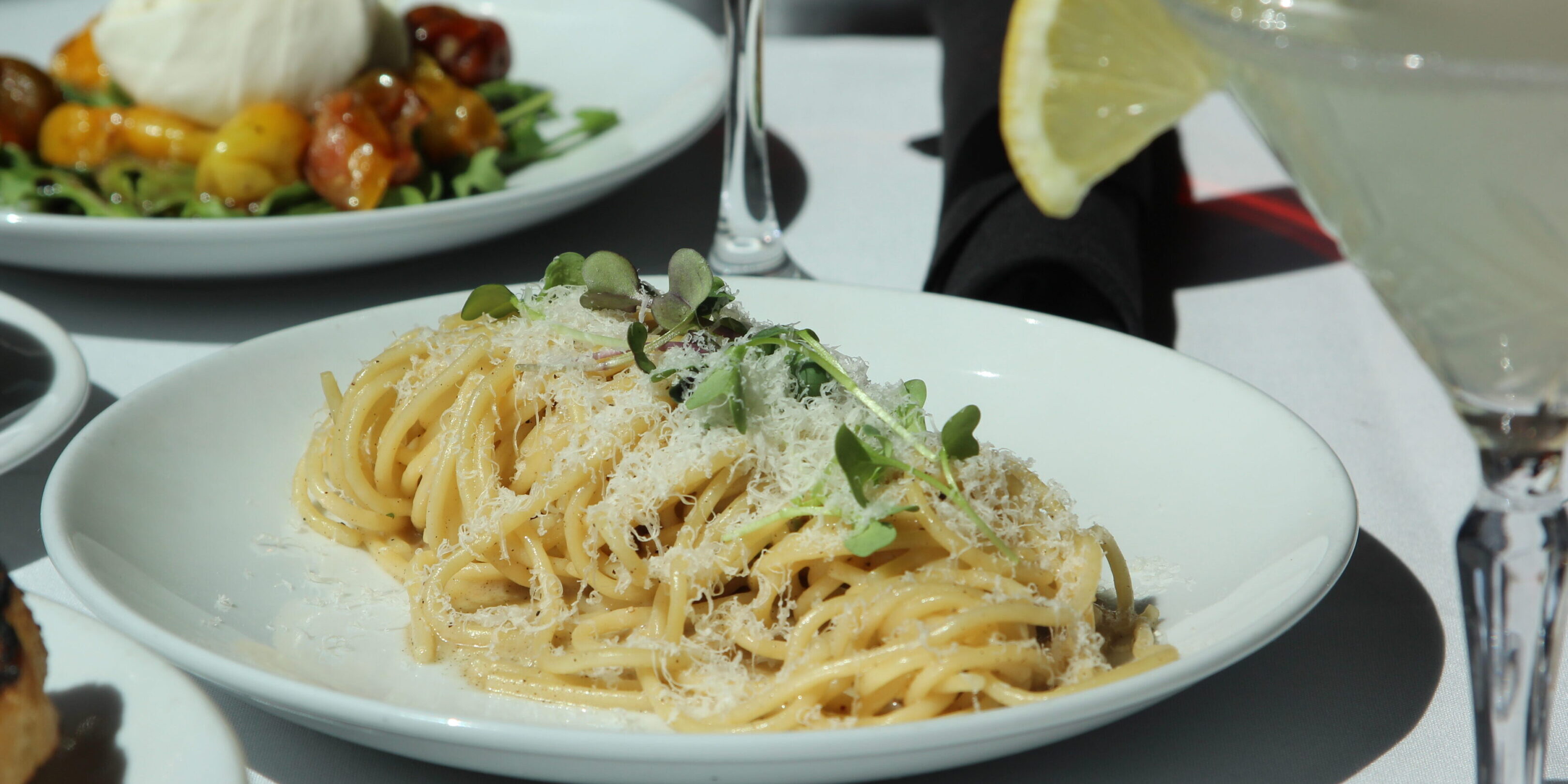 Creamy pasta with green peas and a lemon wedge on the side.